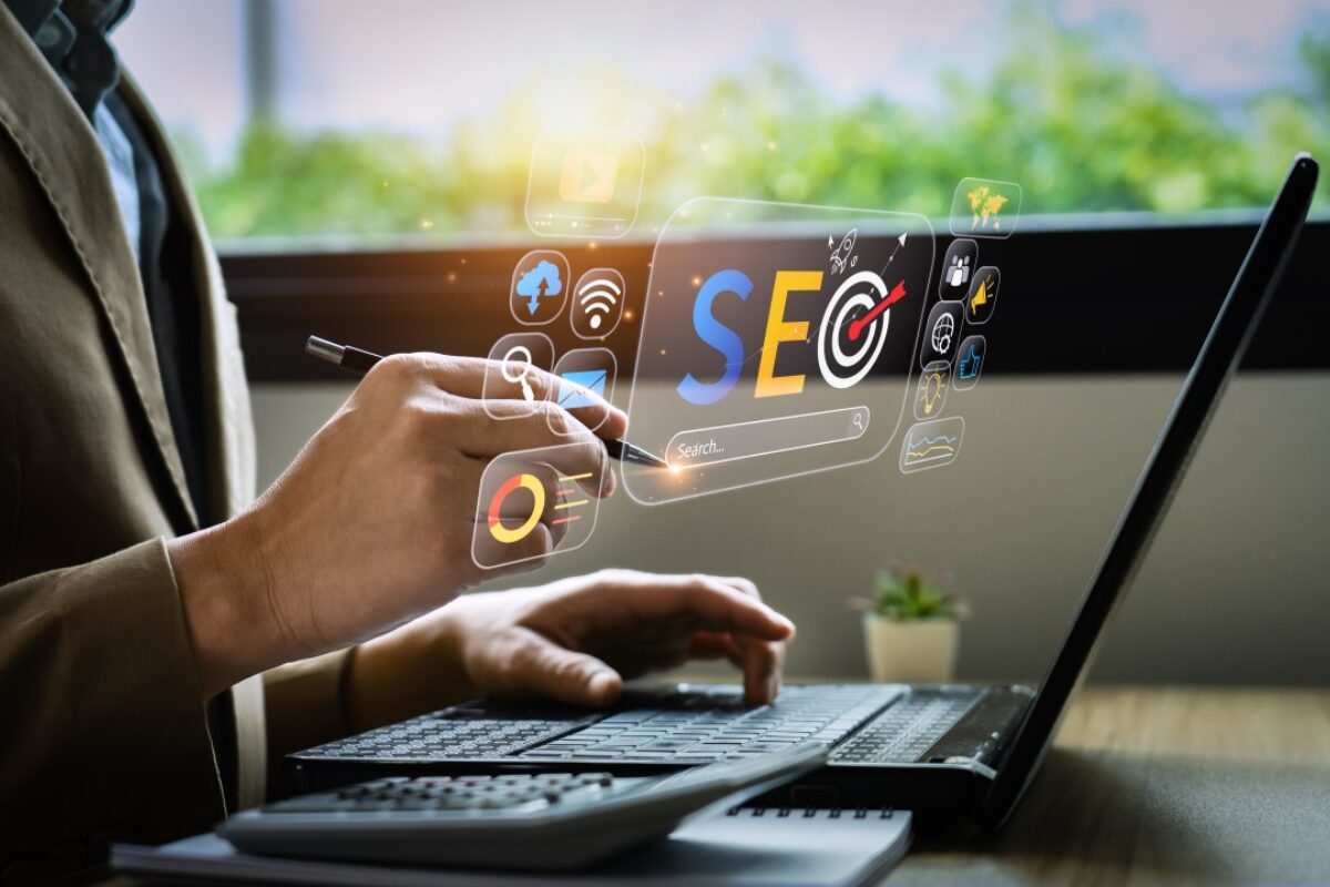 A person uses a laptop displaying digital icons related to SEO and online search optimization.