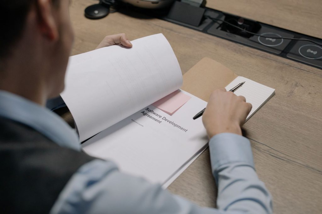 Business professional evaluating self-service implementation guides and pricing documentation on laptop