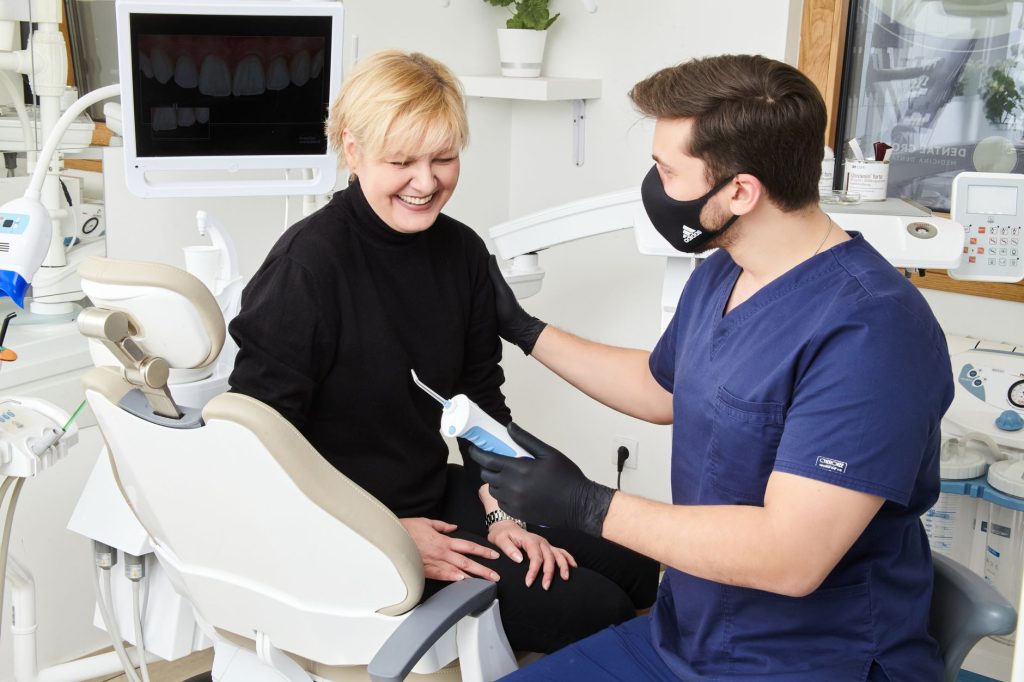 Happy dental patient sharing treatment outcome consultation with dentist