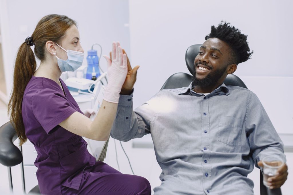 Friendly dental team welcoming patient into comfortable modern clinic treatment room