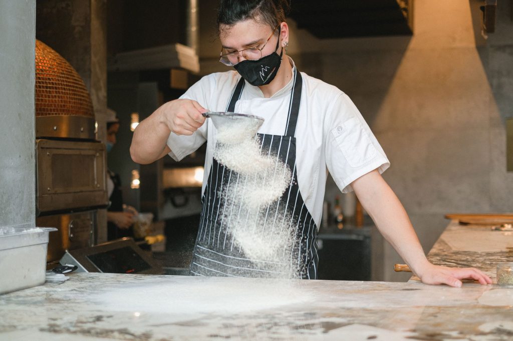 Hotel chef garnishing breakfast plates in sunlit open kitchen for behind-the-scenes content