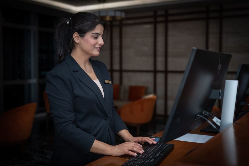 Front desk concierge answering guest inquiry messages on tablet at modern reception