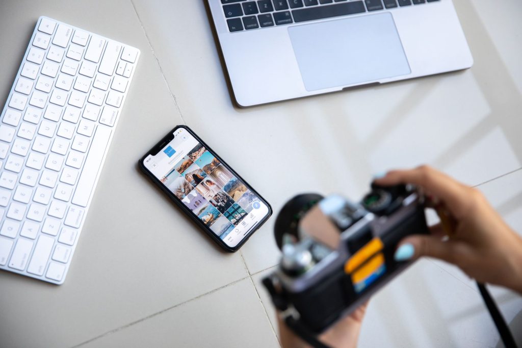Content creator using a smartphone and laptop for social media distribution